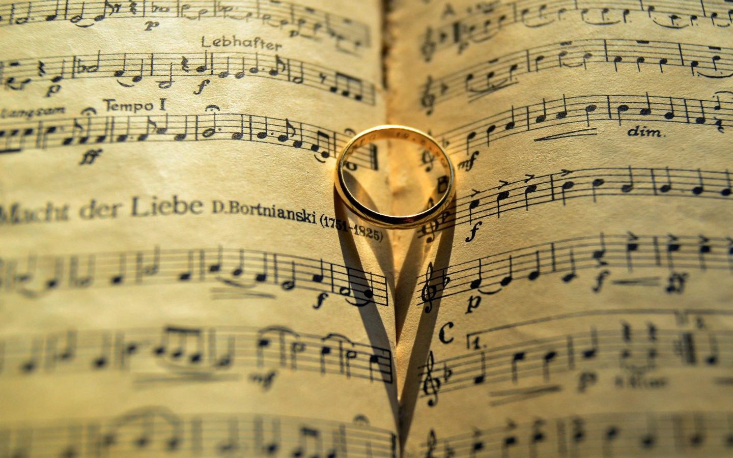 Золотое обручальное кольцо лежит на нотной тетради