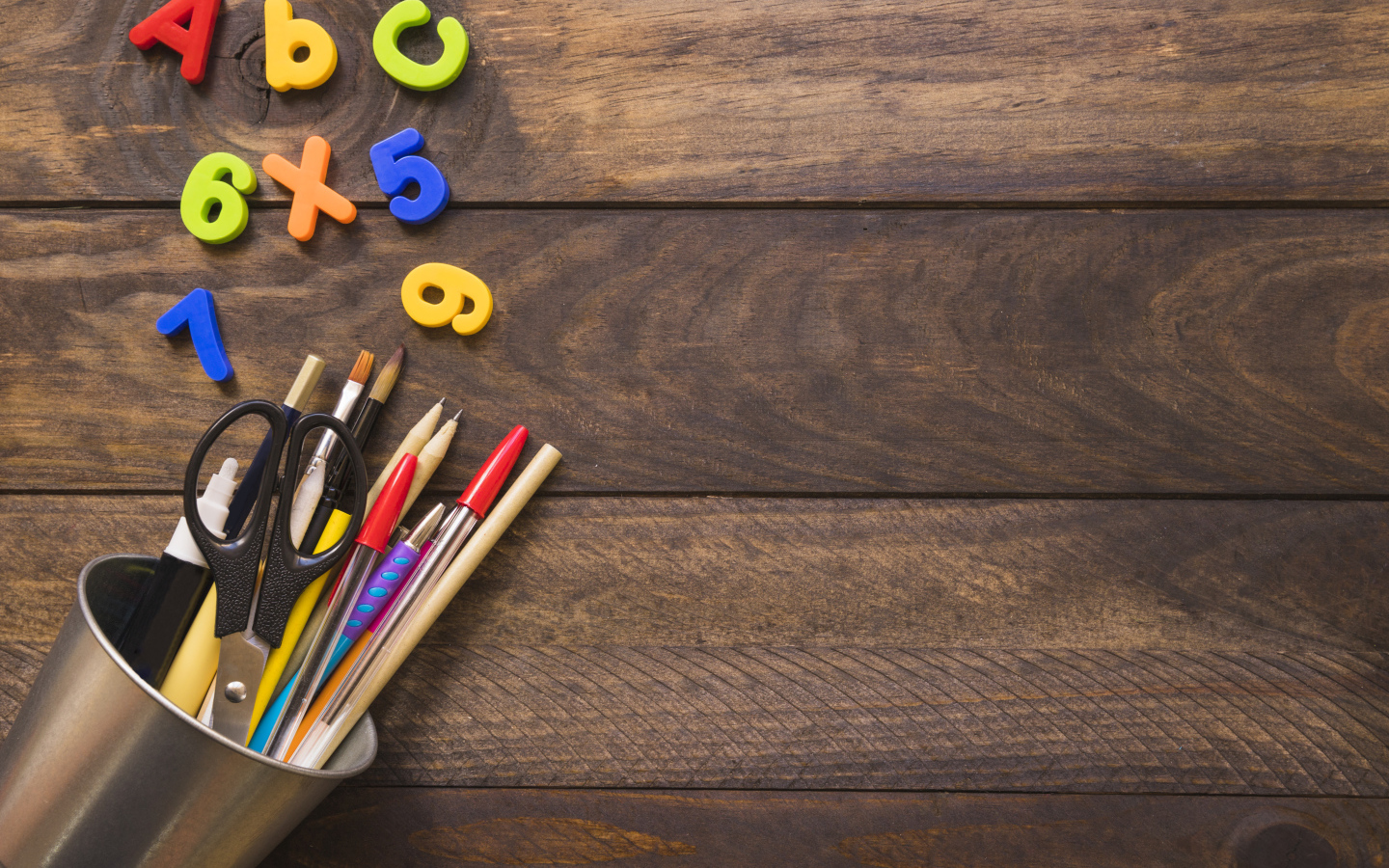 Банка с канцелярскими принадлежностями на деревянном столе с цифрами