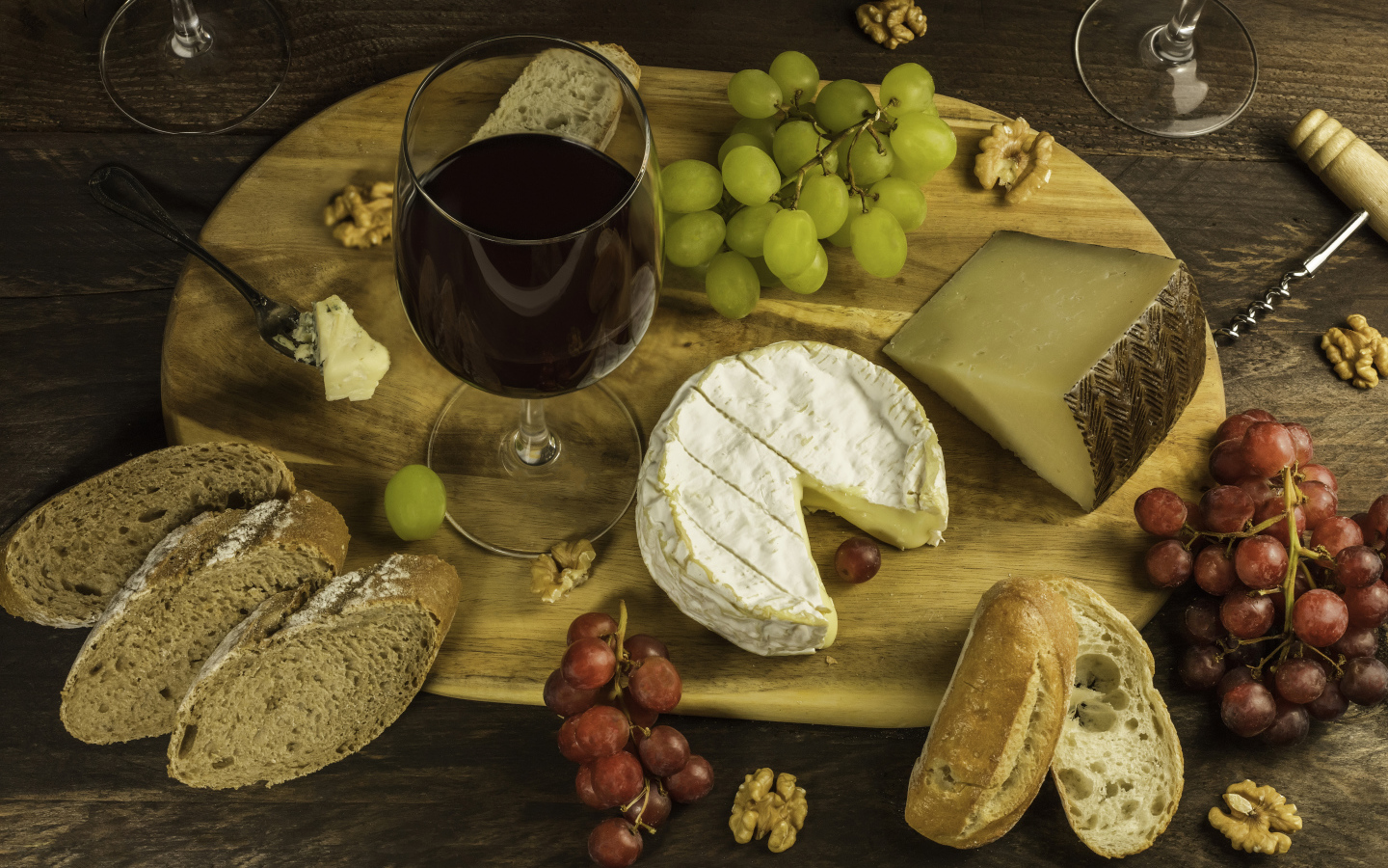Сыр на столе с орехами, хлебом, виноградом и бокалом вина