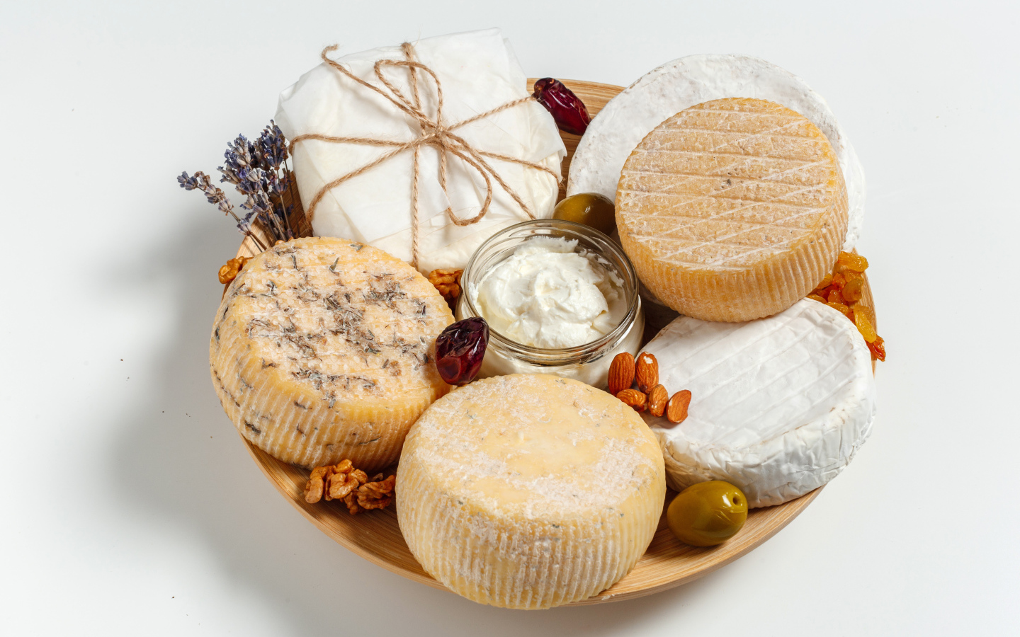 Разные виды сыра на тарелке с орехами на сером фоне