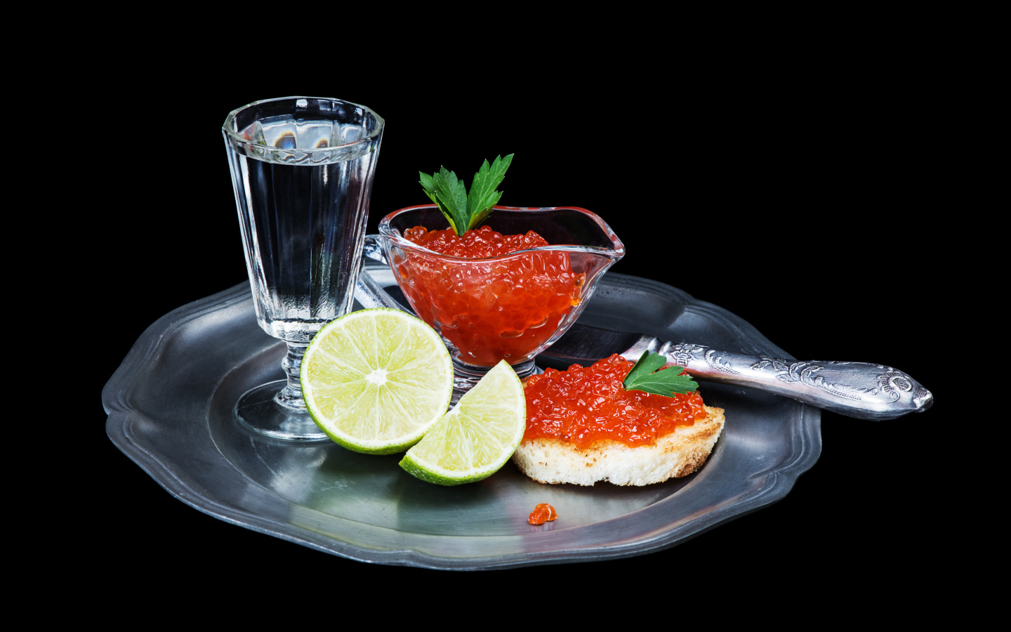 Бутерброды с красной икрой на подносе с рюмкой водки и лаймом