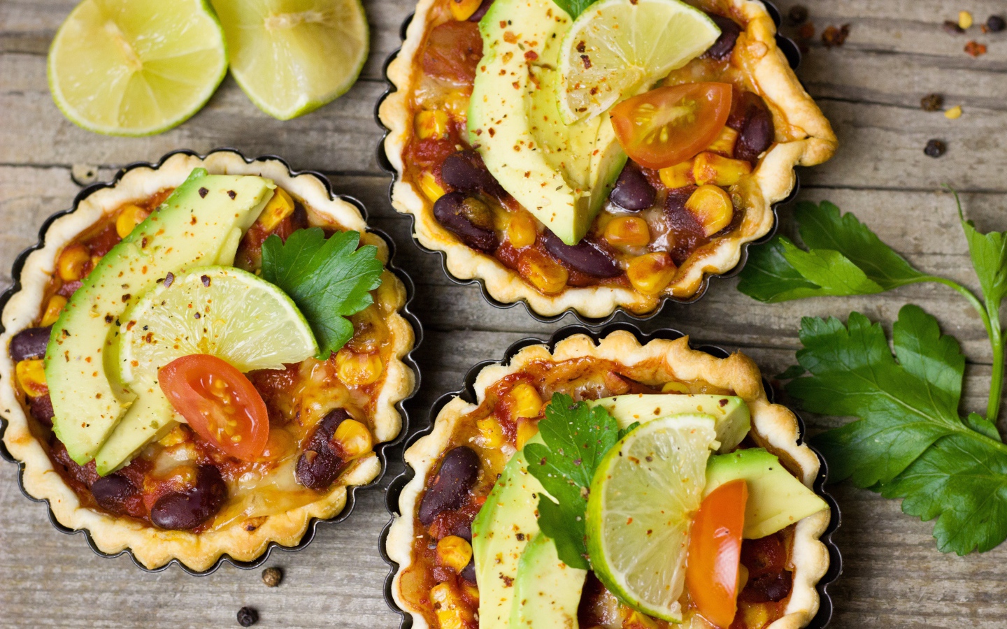 Тарталетки с блюдом, кусочками авокадо и лайма на столе