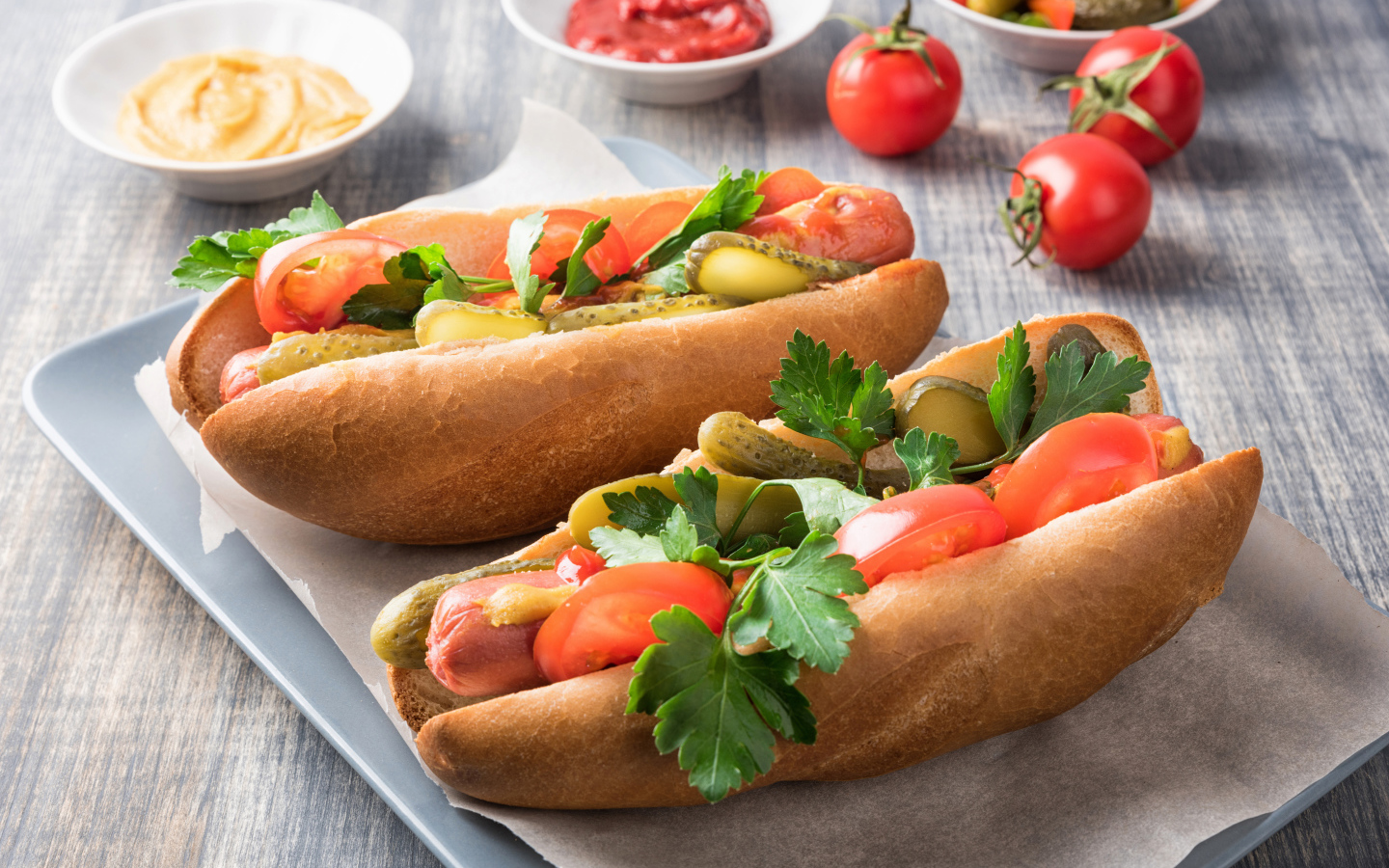 Two hotdogs with sausage, cucumbers and tomatoes