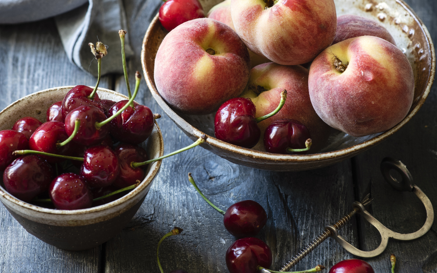 Спелые персики в миске на столе с черешней