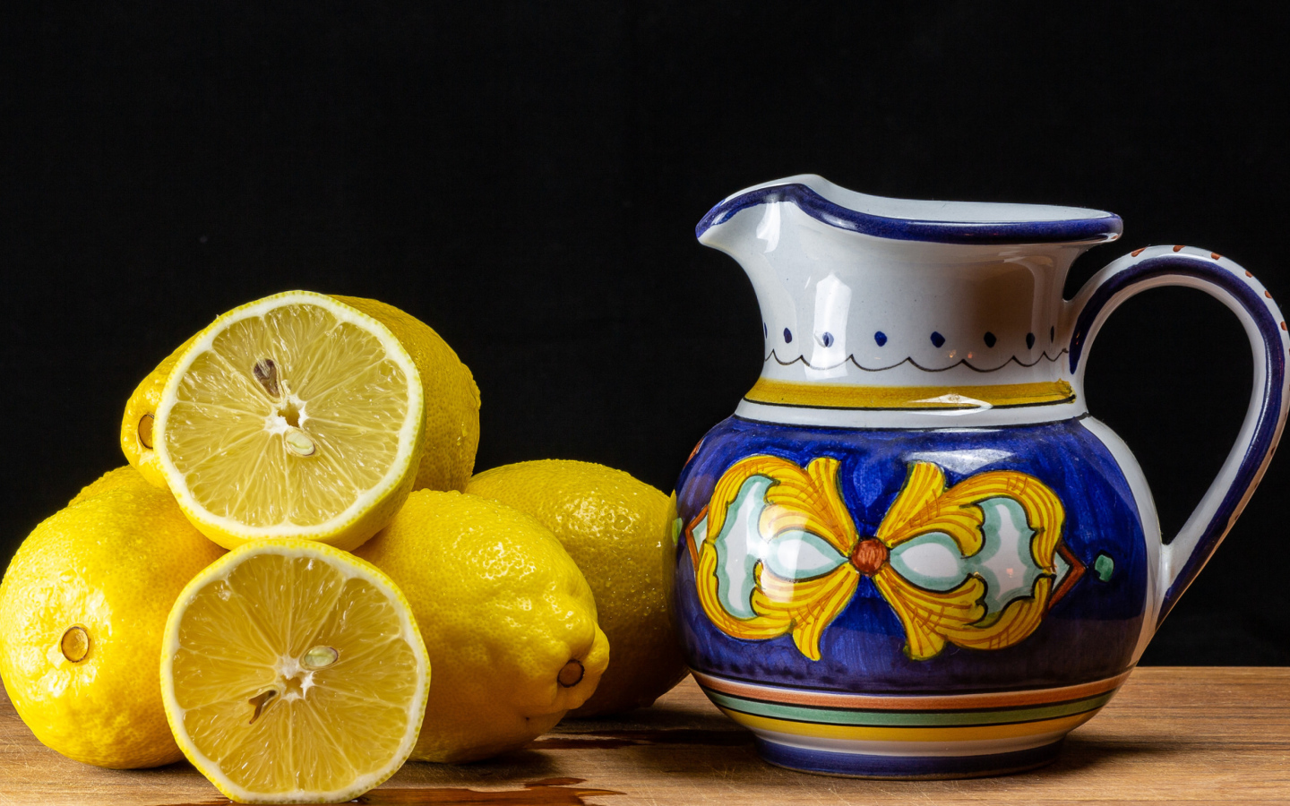 Желтые лимоны на столе с кувшином