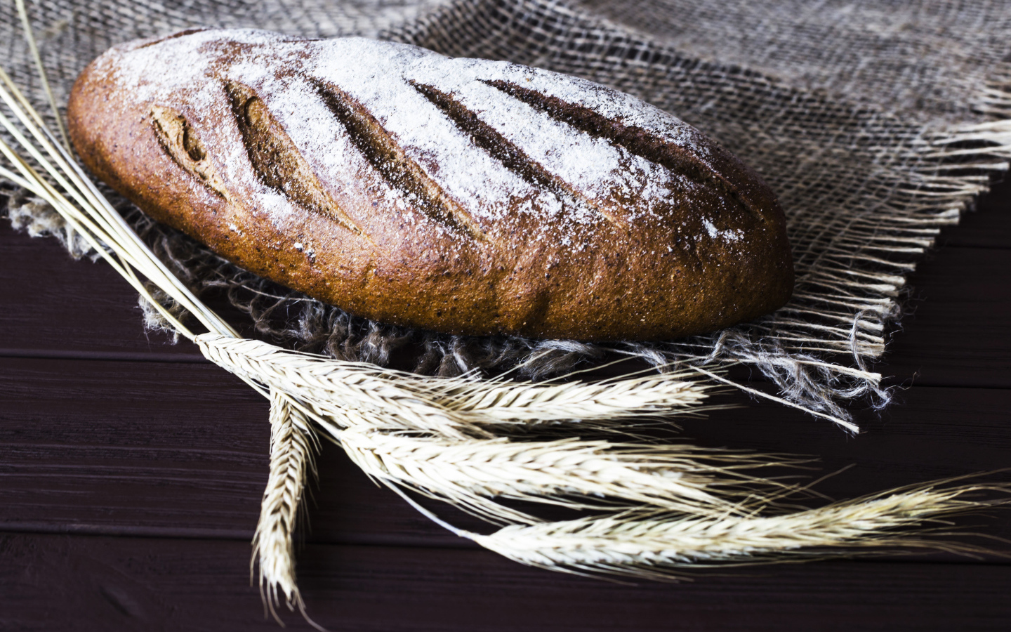 Буханка свежего хлеба на столе с колосьями пшеницы