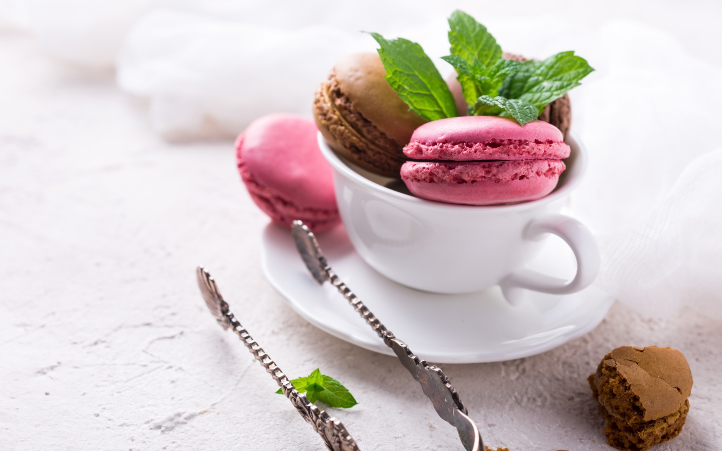 Разноцветный десерт макарун в белой чашке на столе