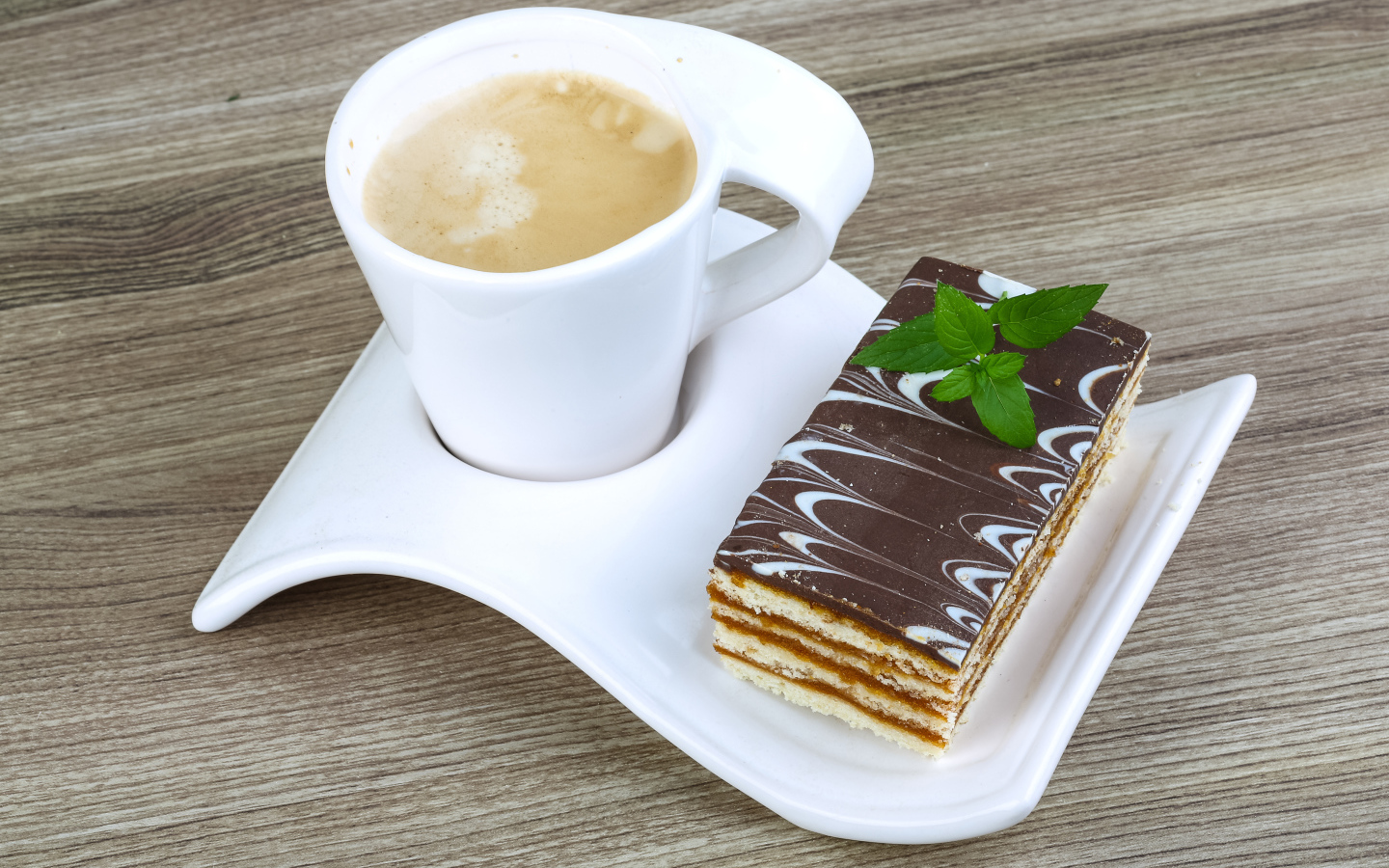 Чашка капучино на тарелке с пирожным 