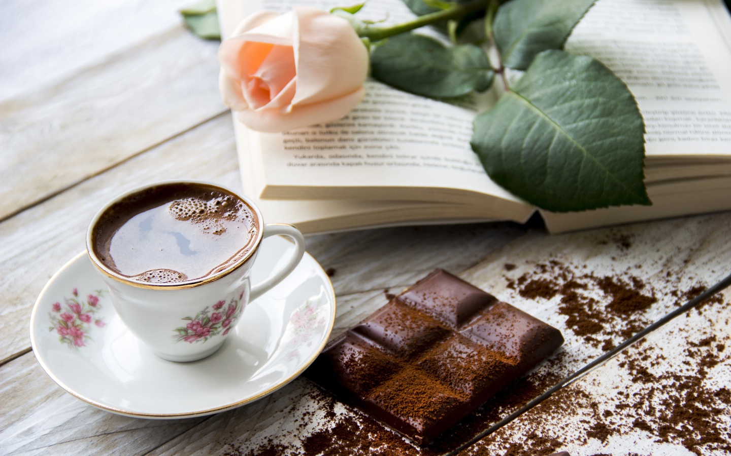 Чашка кофе на столе с шоколадом, книгой и розой