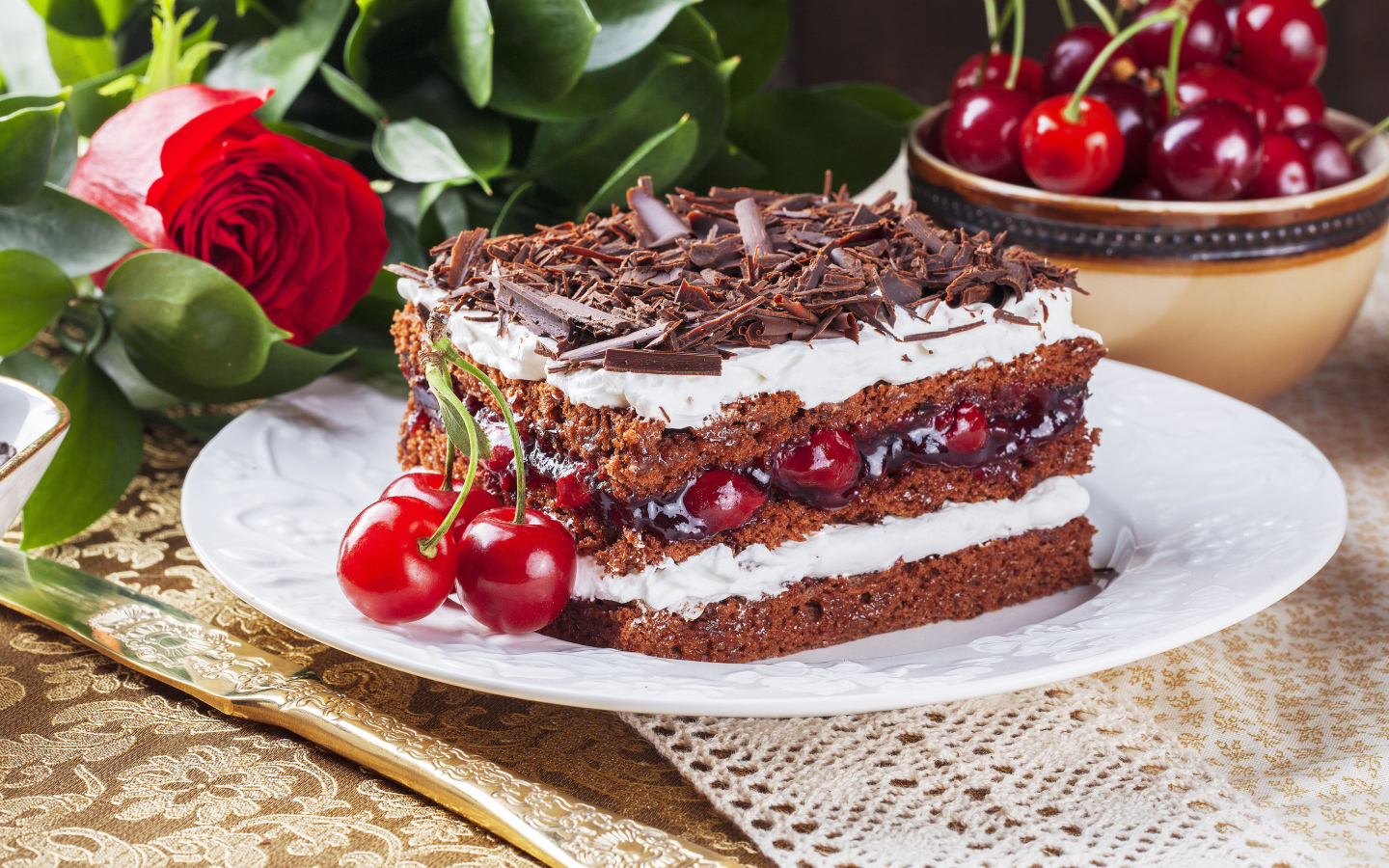 Кусок торта с вишней, шоколадной крошкой на столе с розой