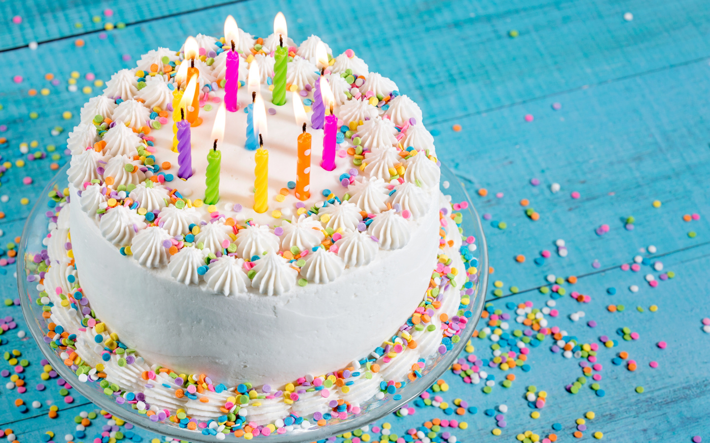 Большой праздничный торт с кремом и свечами на голубом столе