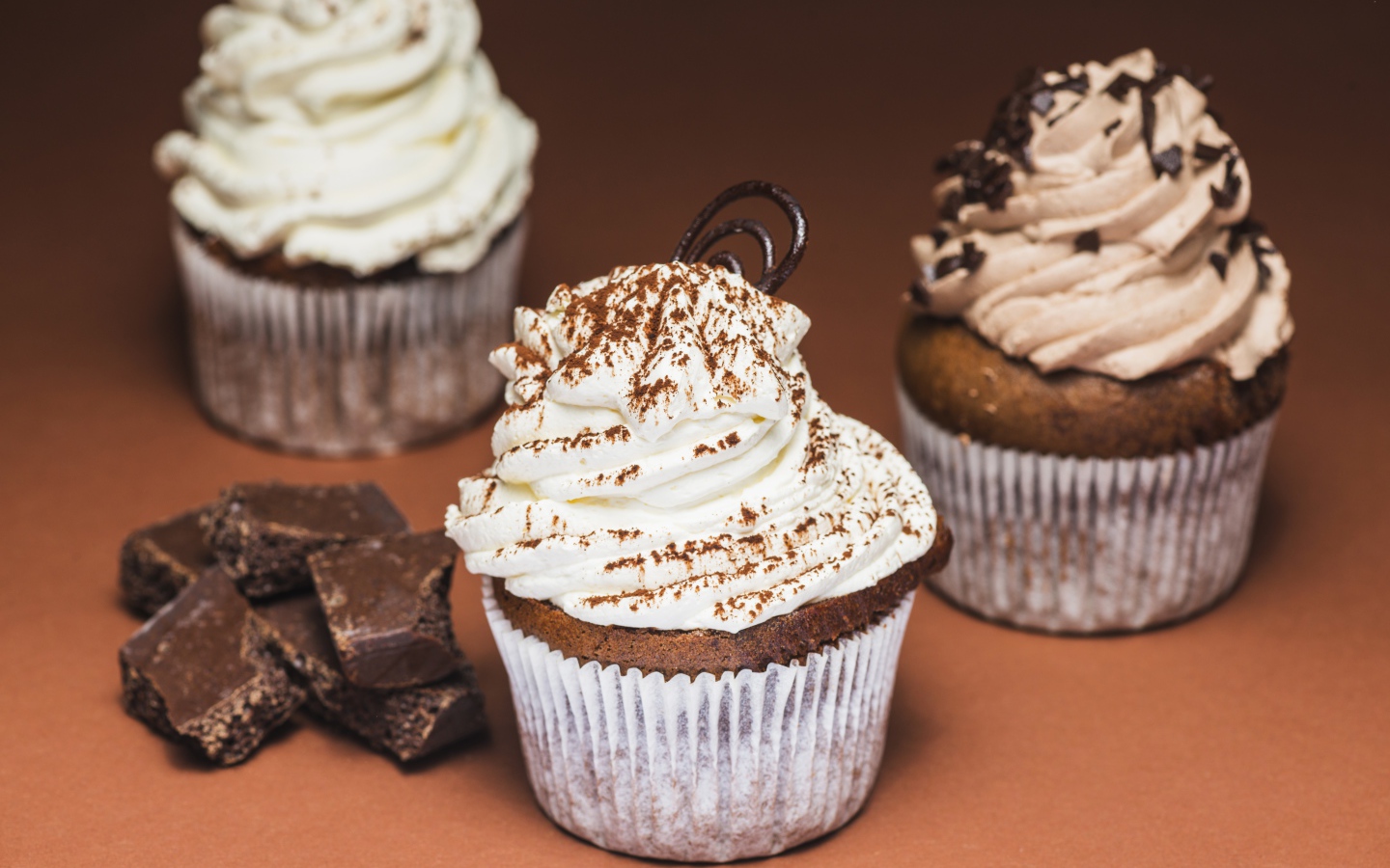 Кексы с кремом на столе с кусочками шоколада 