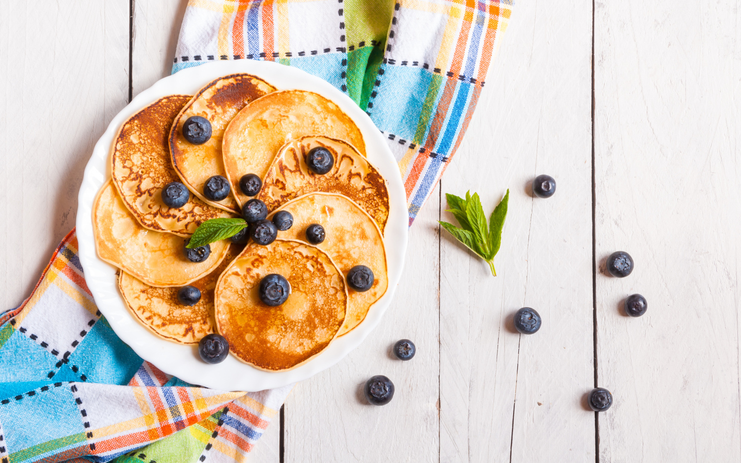Румяные оладьи на тарелке с ягодами черники