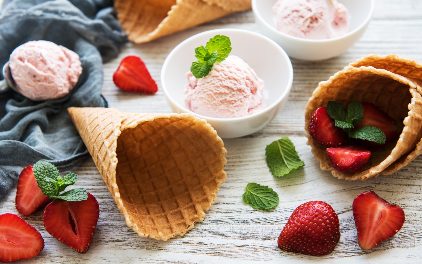 Клубничное мороженое на столе с рожками и клубникой