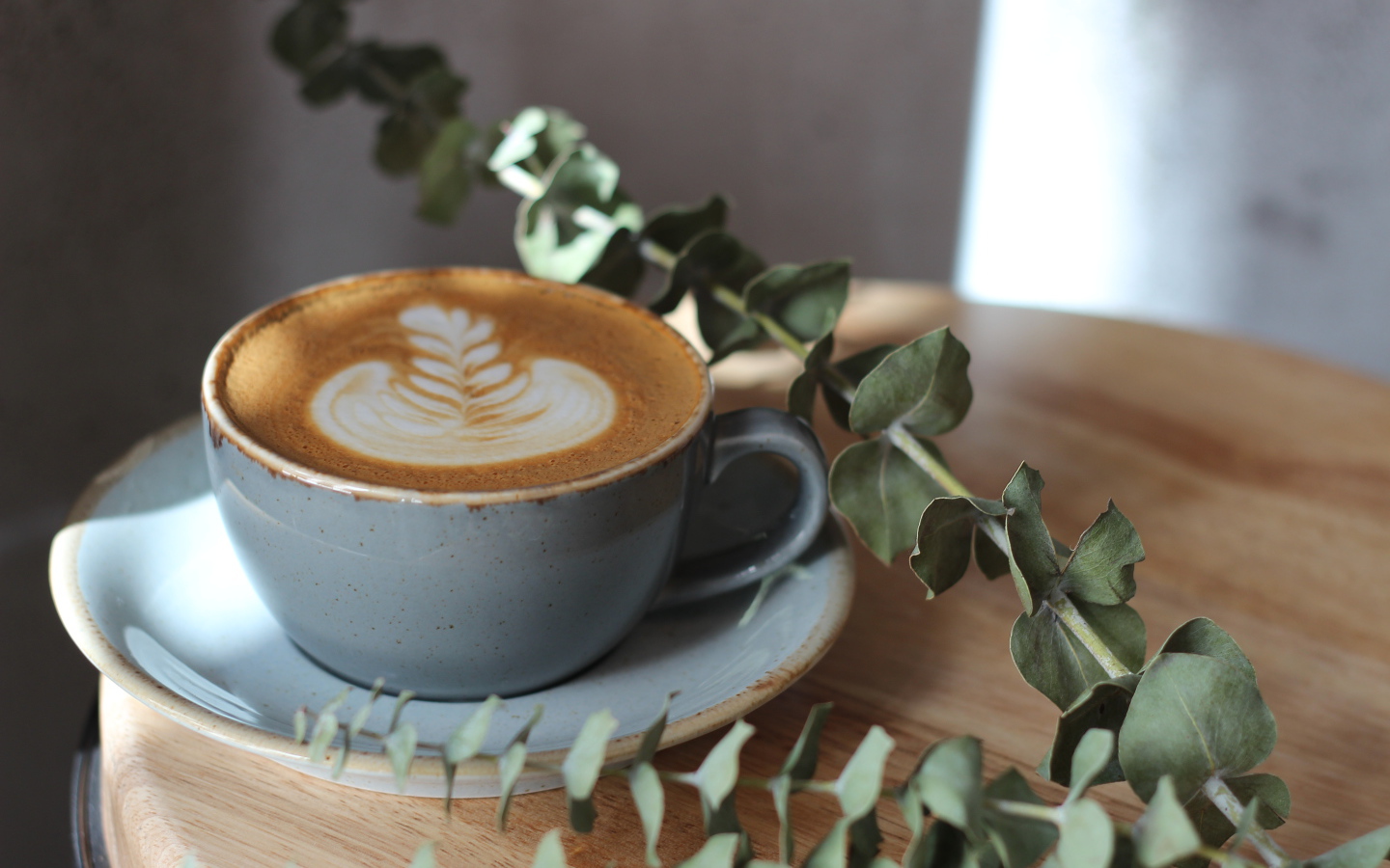 Большая чашка кофе с рисунком на пене на столе с веткой