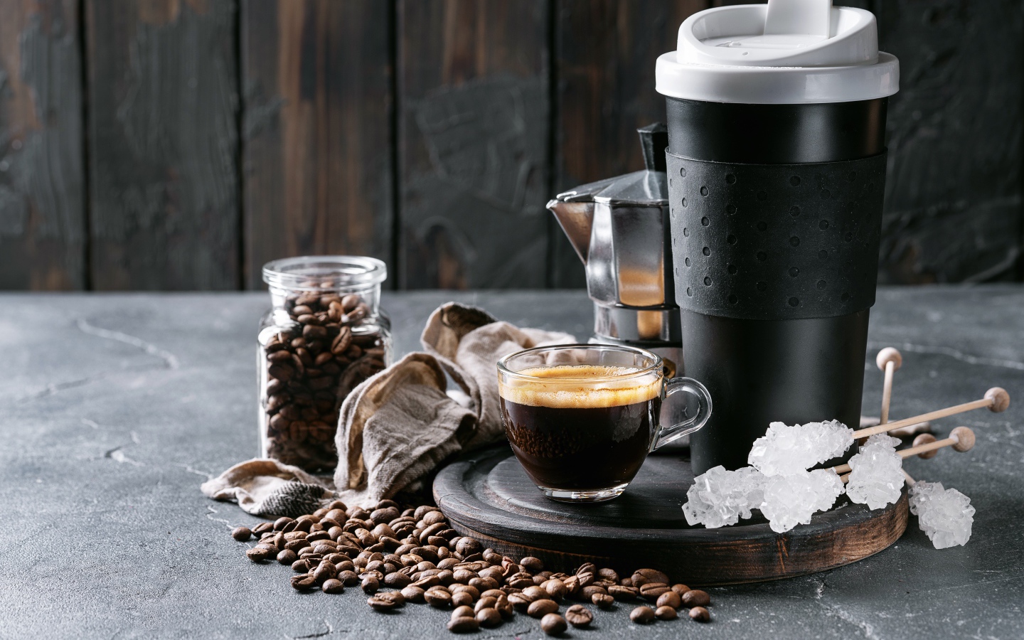 Стеклянная чашка кофе на столе с термосом и зернами