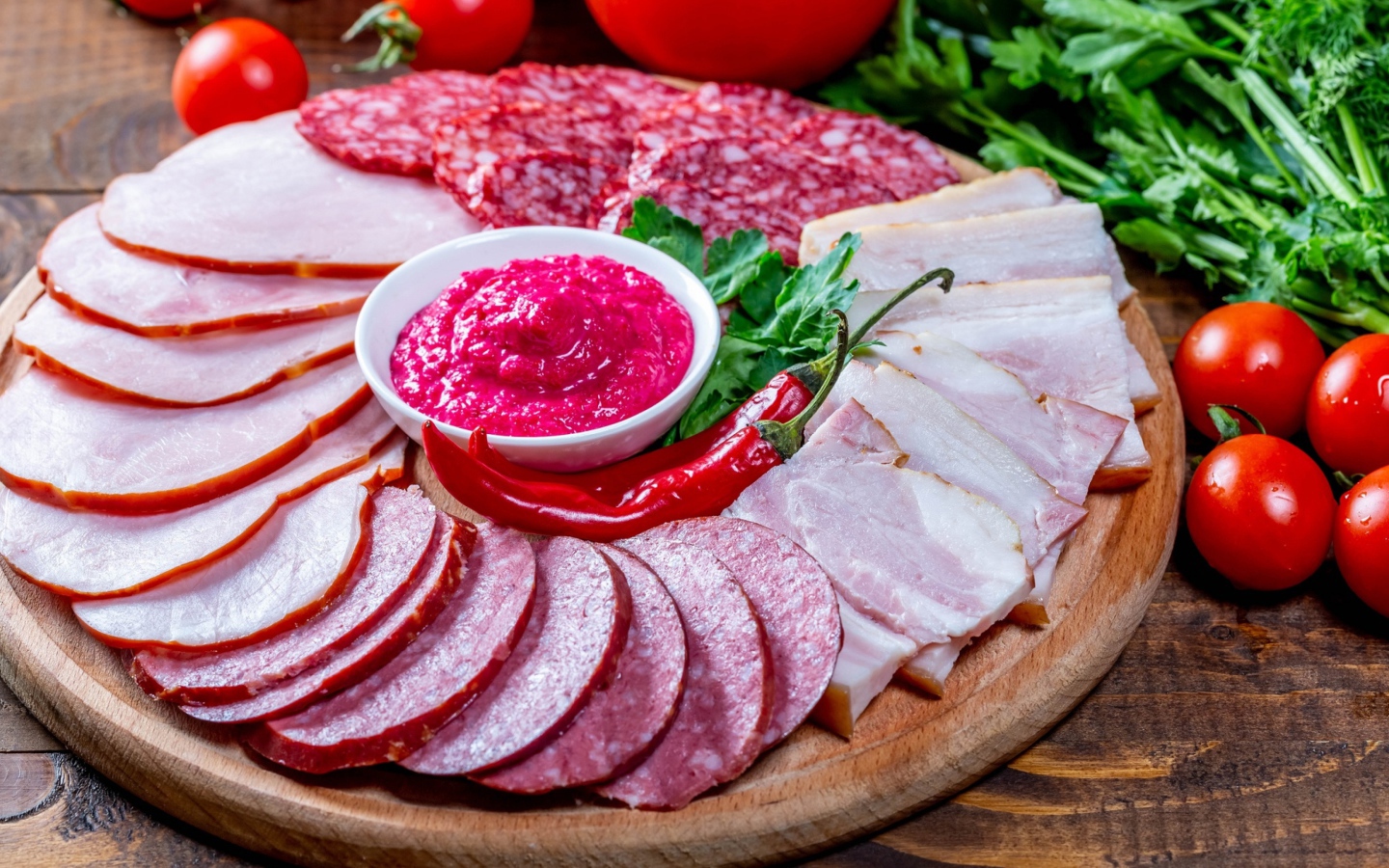 Мясная нарезка на доске с соусом, красным перцем,  помидорами и зеленью 