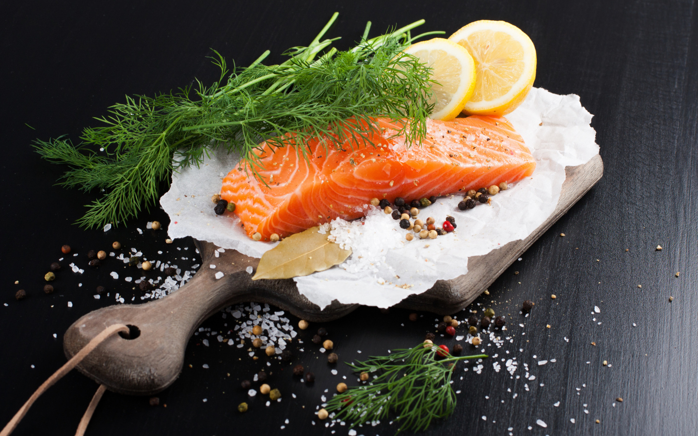 Кусок красной рыбы на доске с укропом и лимоном 