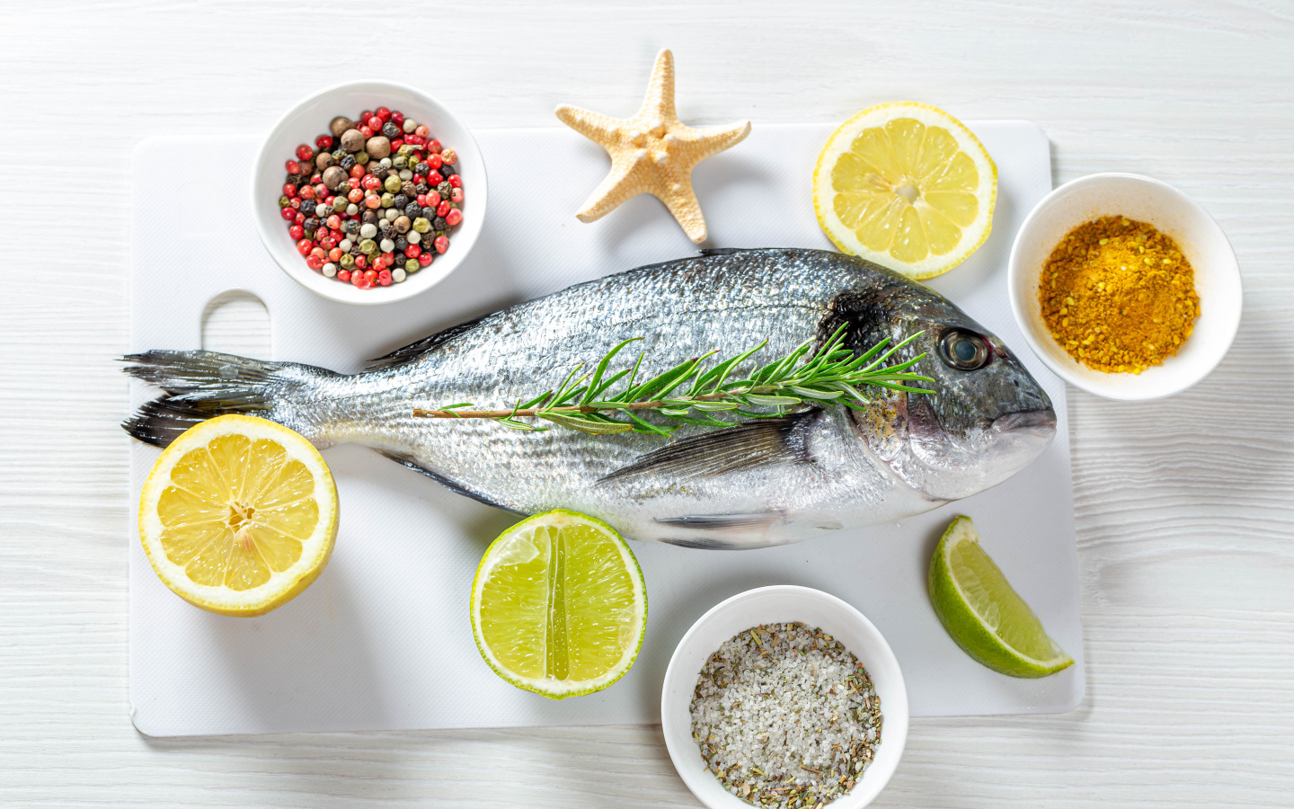 Свежая рыба на доске с солью, перцем, куркумой и лимоном