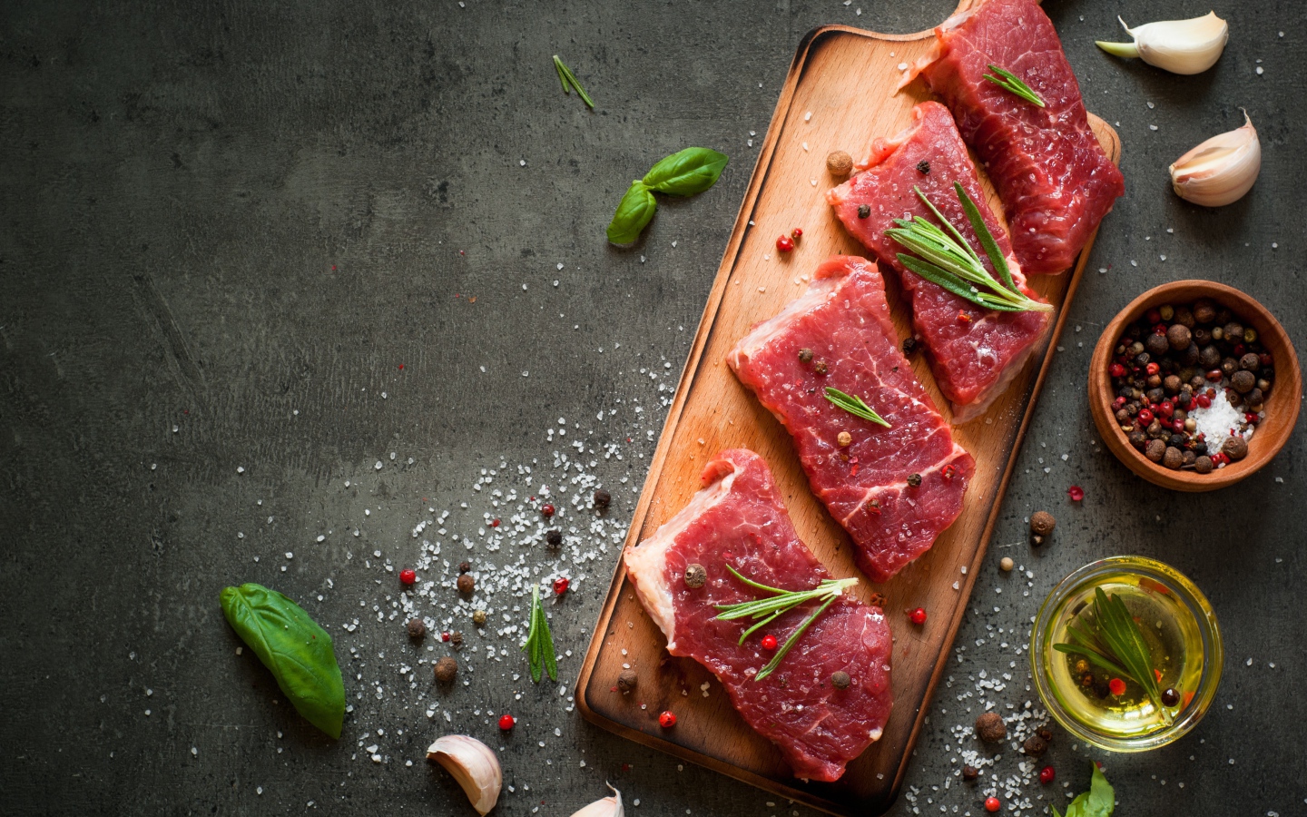 Куски мяса на разделочной доске с зеленью и специями