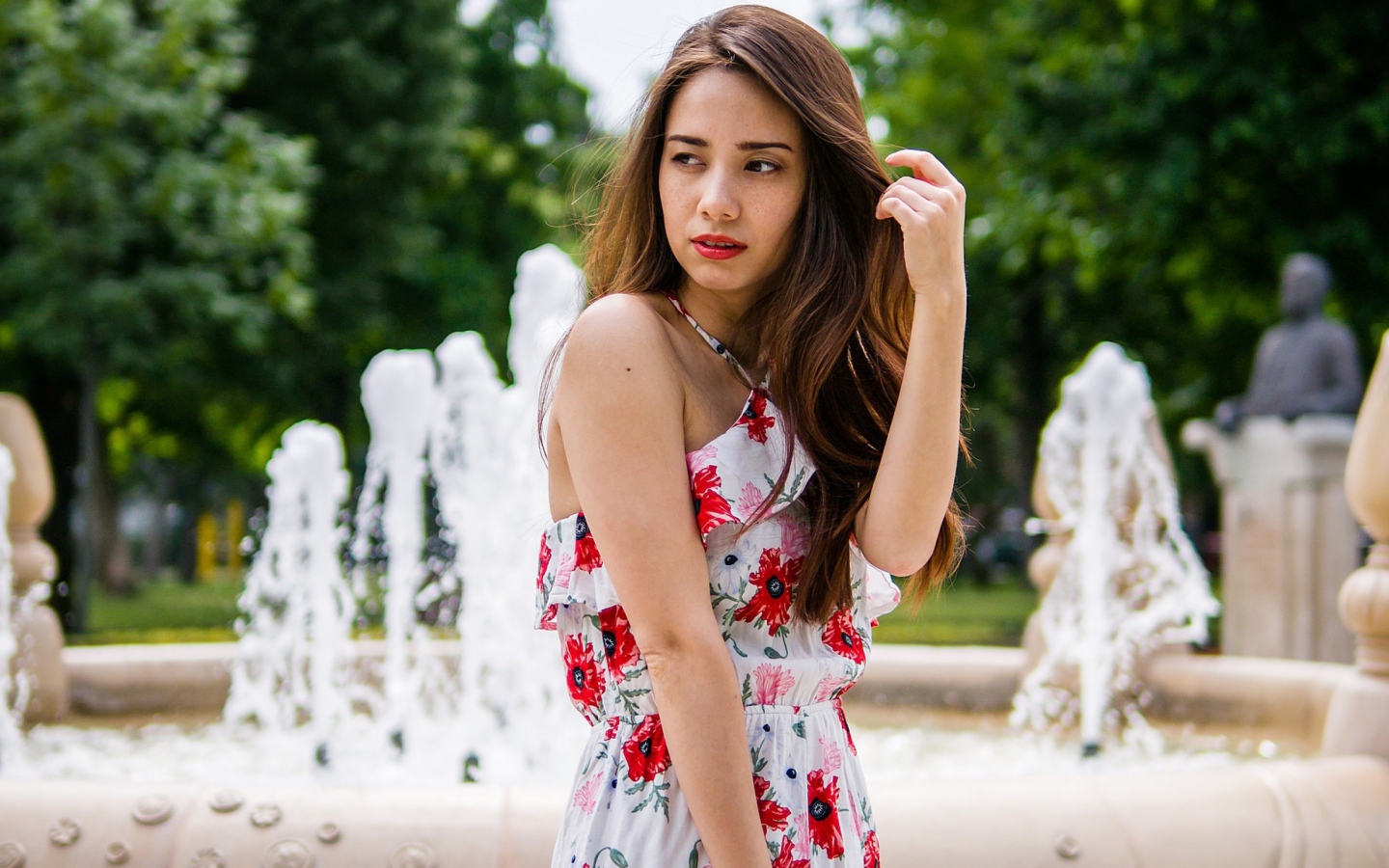 Красивая шатенка в цветастом платье у фонтана летом