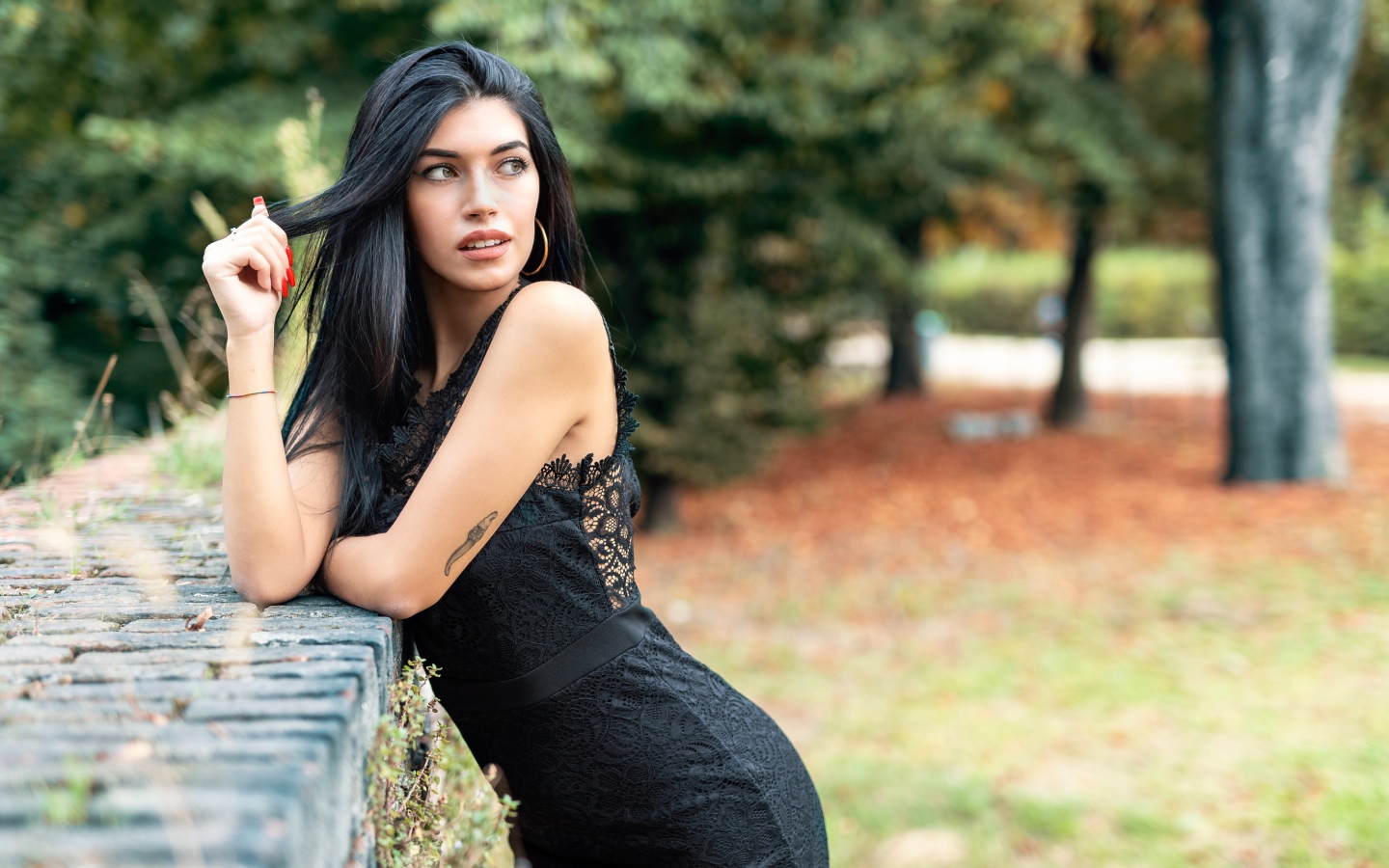 Красивая брюнетка в черном платье в парке