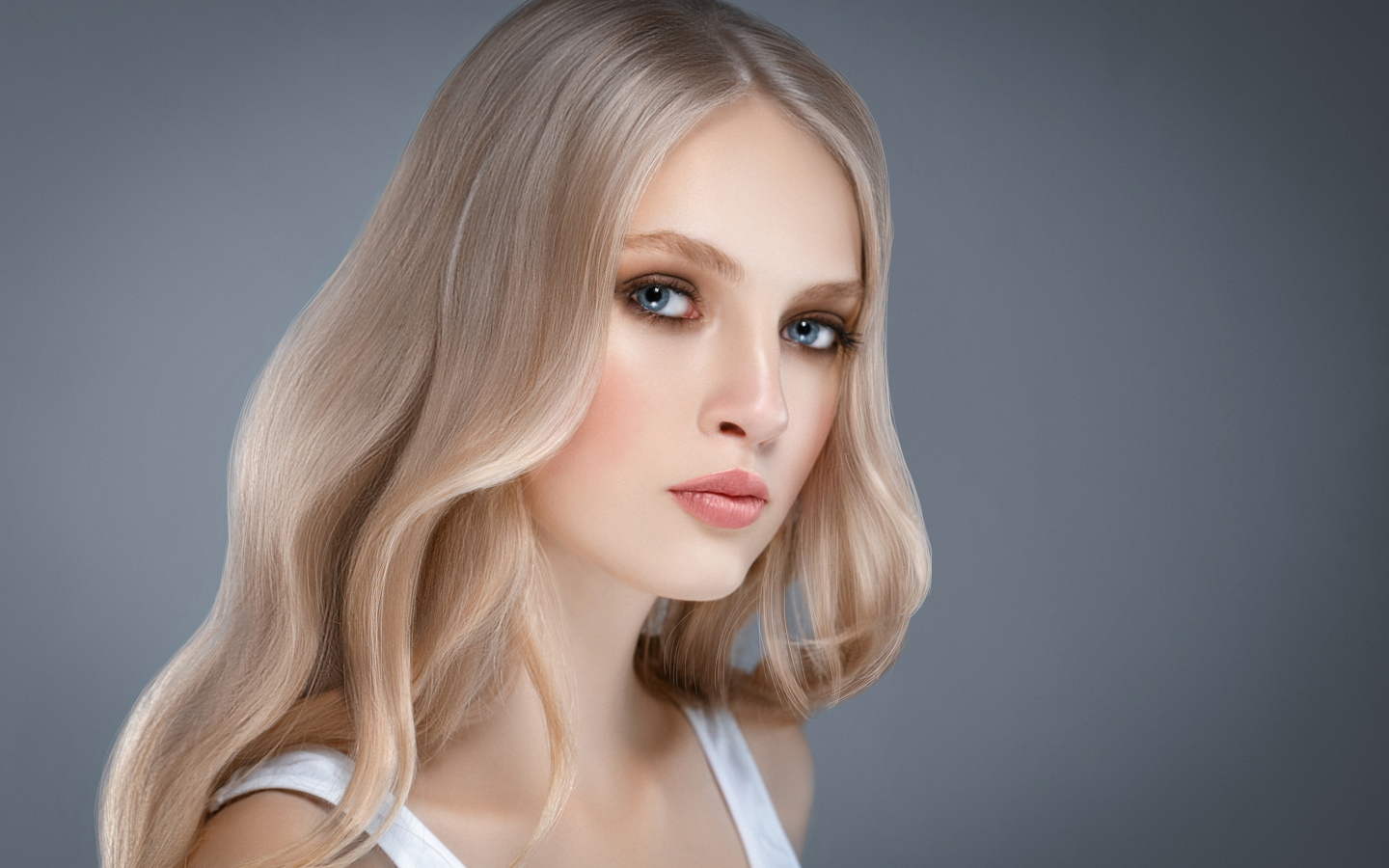 Красивая нежная голубоглазая блондинка на сером фоне