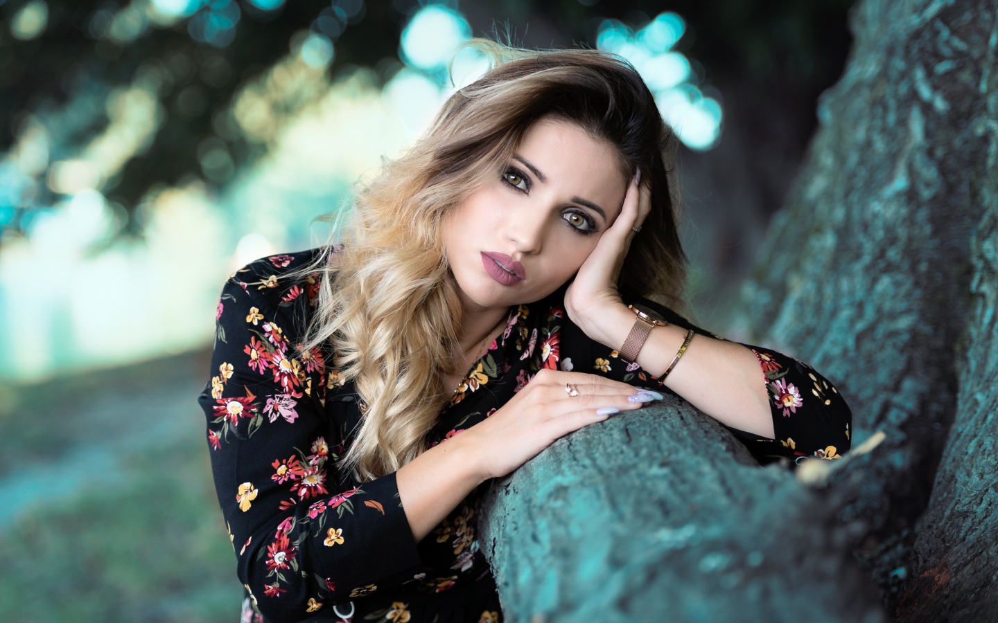 Красивая девушка в цветастом платье у дерева