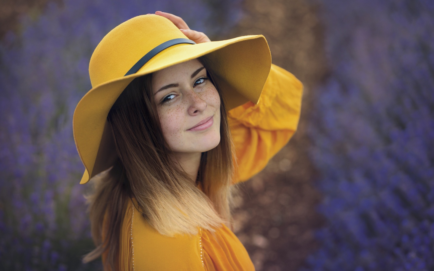 Красивая девушка с веснушками на лице в желтой шляпе