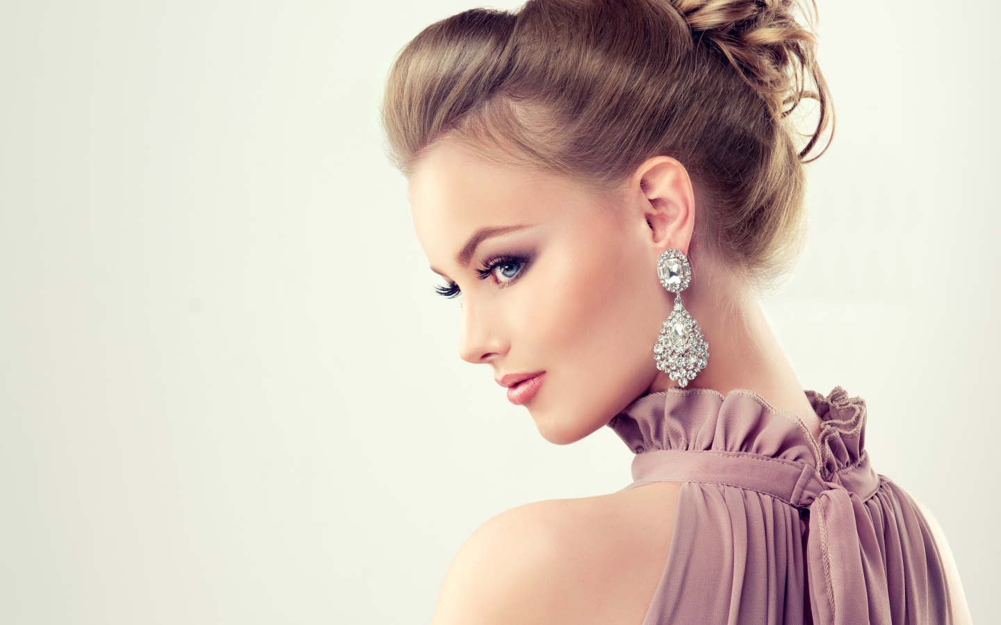 Красивая девушка с макияжем и прической на сером фоне