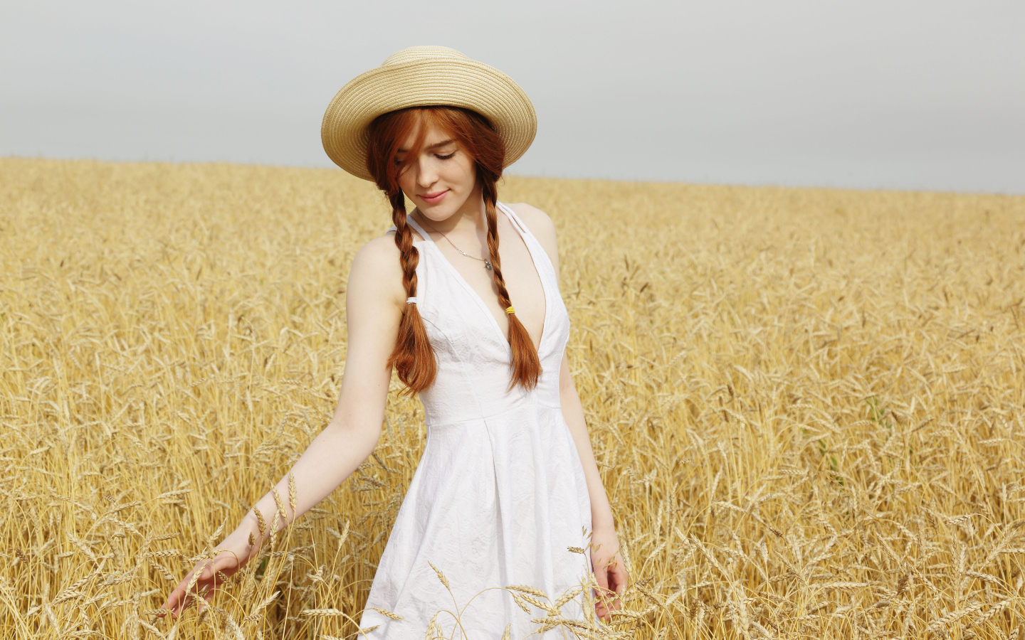 Красивая рыжеволосая девушка гуляет по полю с пшеницей