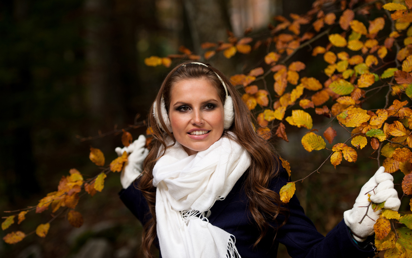 Девушка шатенка с белым шарфом стоит у дерева с желтыми листьями