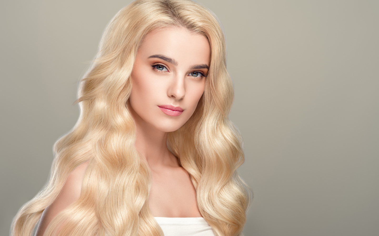 Милая длинноволосая блондинка на сером фоне