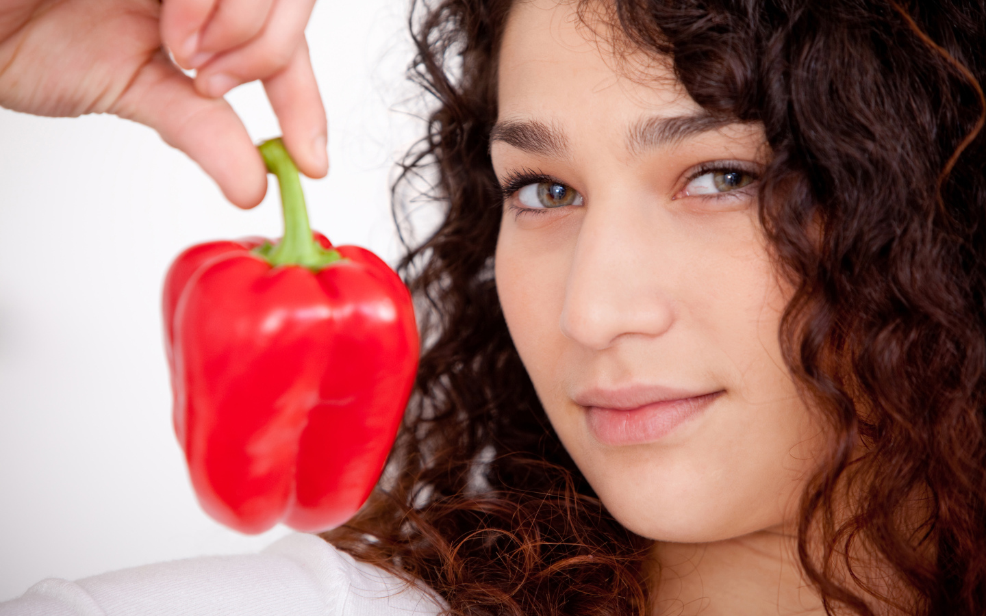 Лицо девушки с красным сладким перцем в руке крупным планом