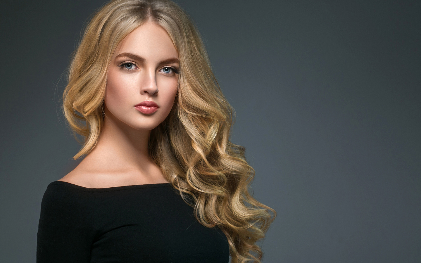 Длинноволосая блондинка с голубыми глазами на сером фоне