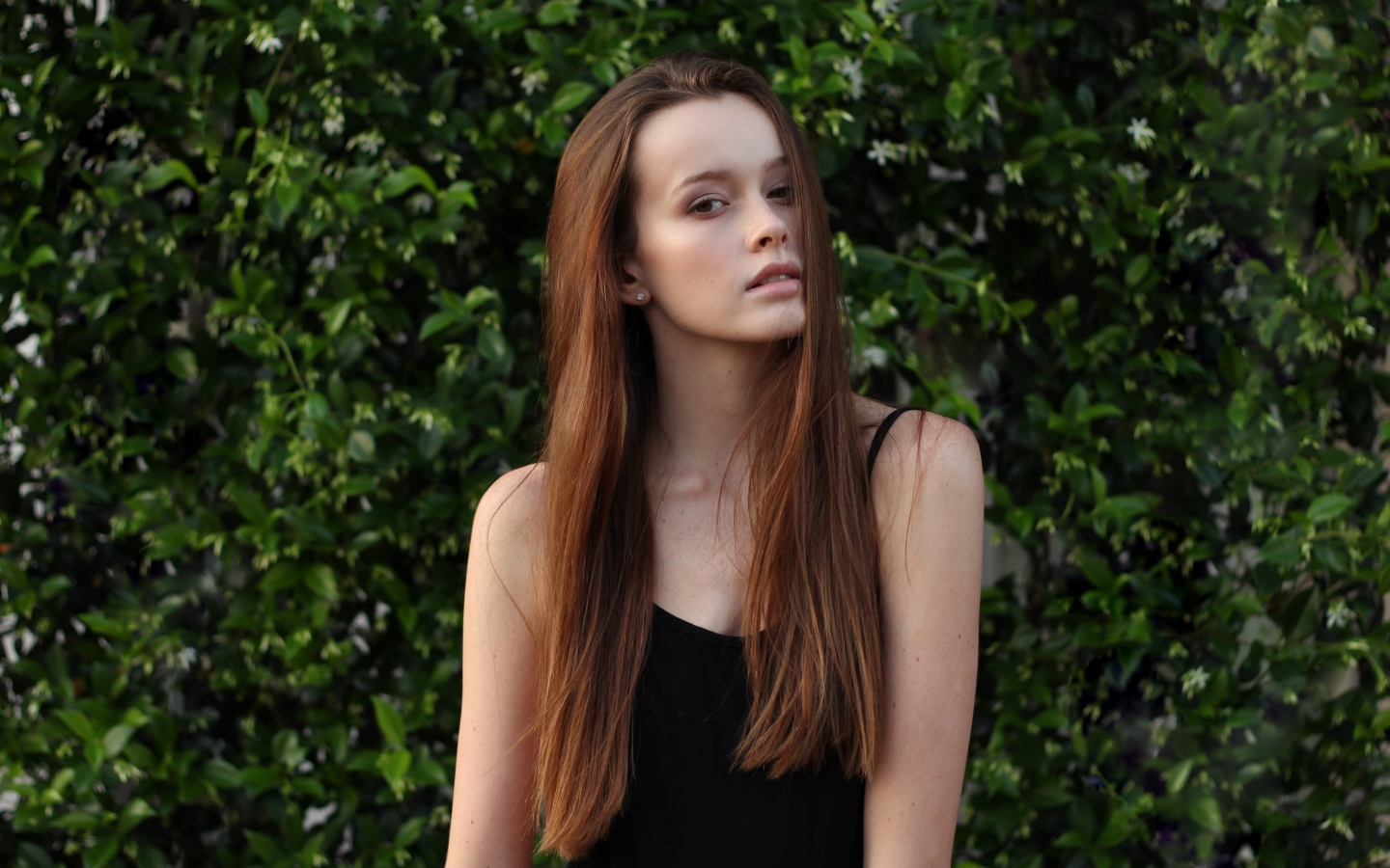 Длинноволосая шатенка на фоне зеленых зарослей