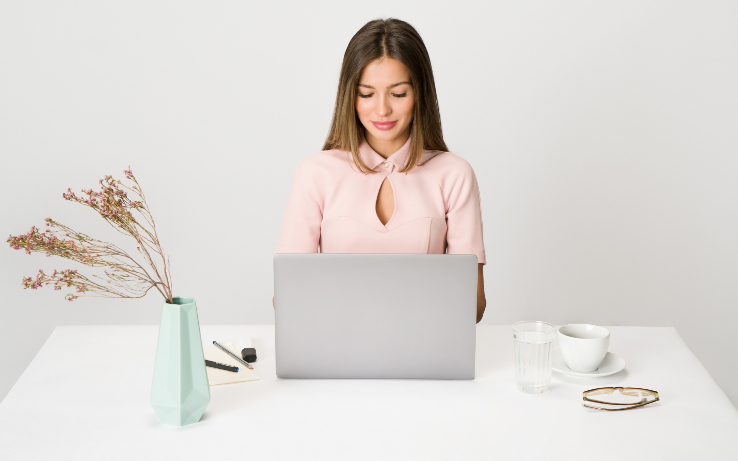 Умная девушка за ноутбуком на сером фоне