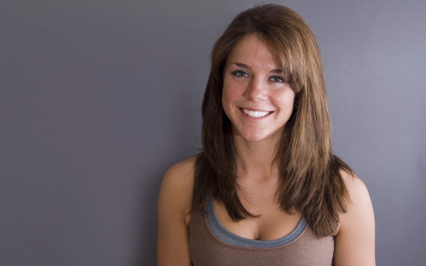 Улыбающаяся милая девушка у серой стены