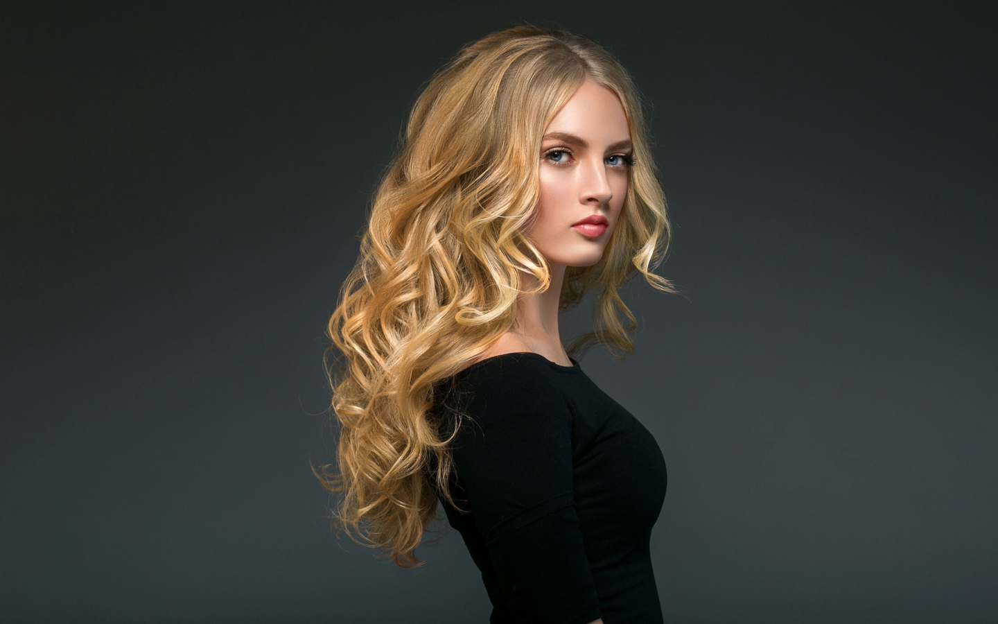 Стильная голубоглазая длинноволосая девушка в черном наряде