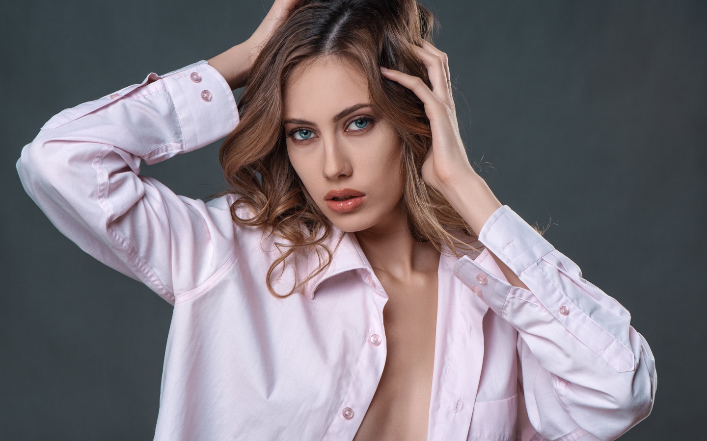 Стильная девушка в розовой рубашке на сером фоне