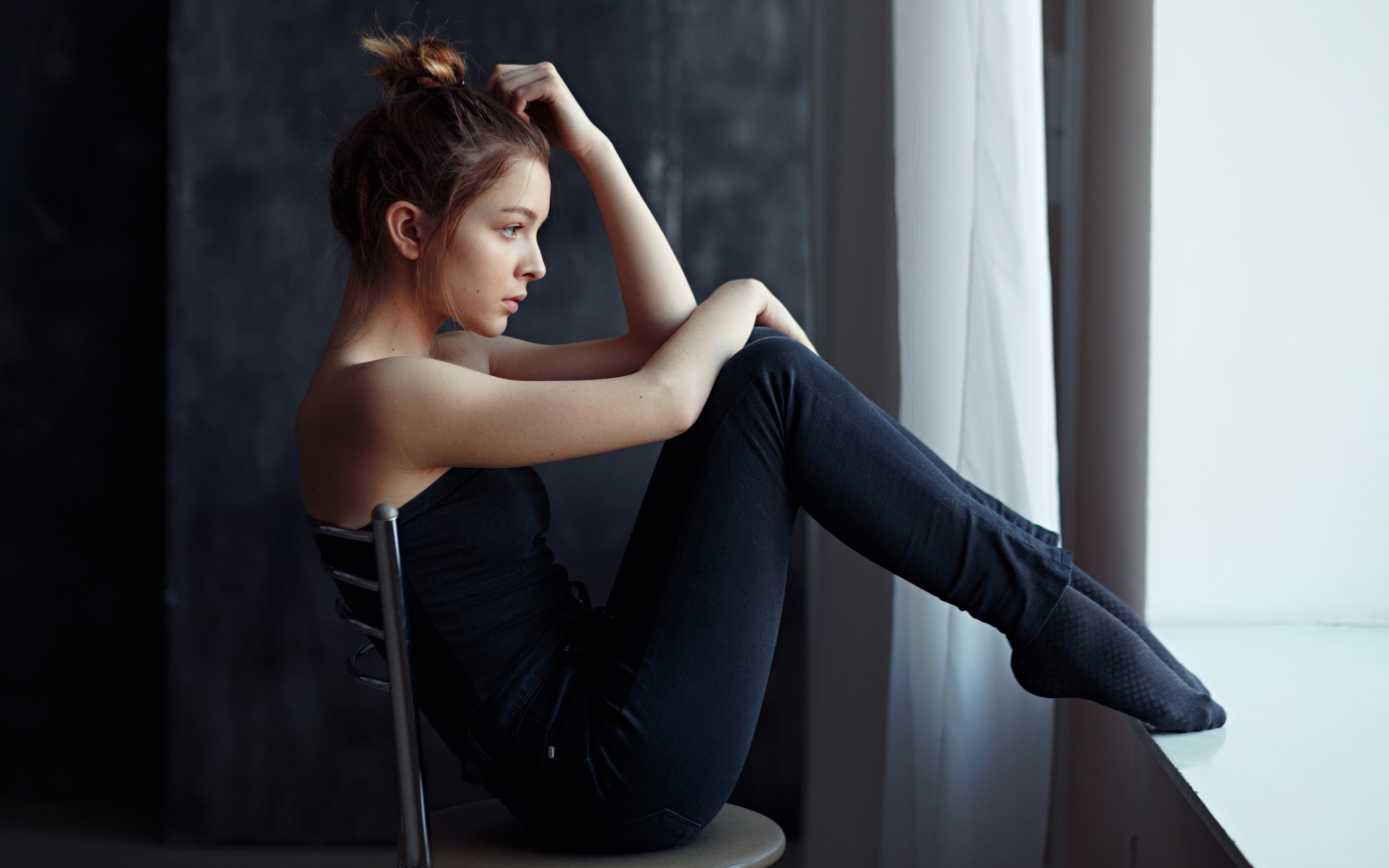 Девушка в черном наряде сидит на стуле