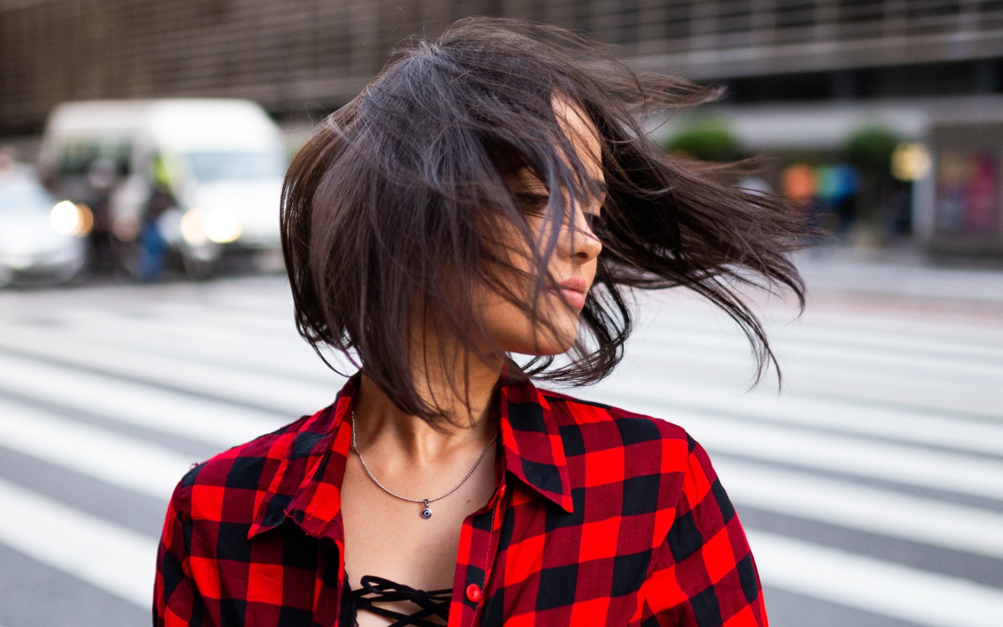 Ветер развивает волосы красивой шатенки в клетчатой рубашке