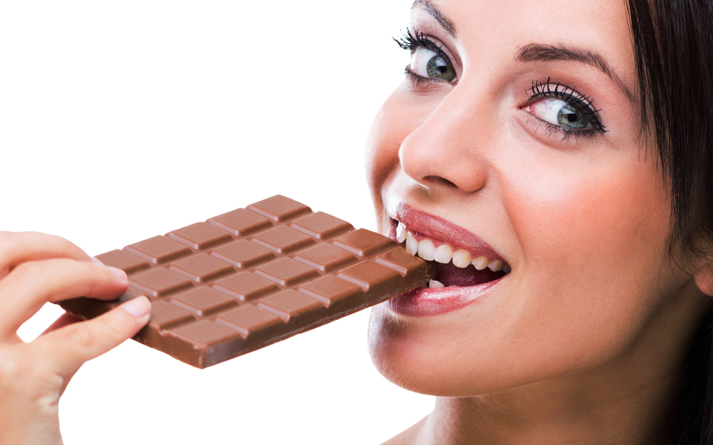 Молодая девушка кусает молочную шоколадку на белом фоне