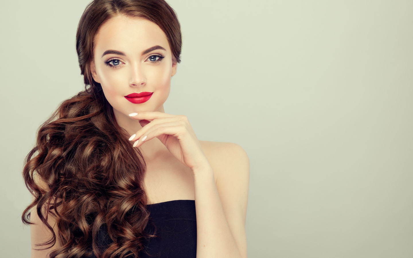 Молодая девушка с красивыми волосами на сером фоне