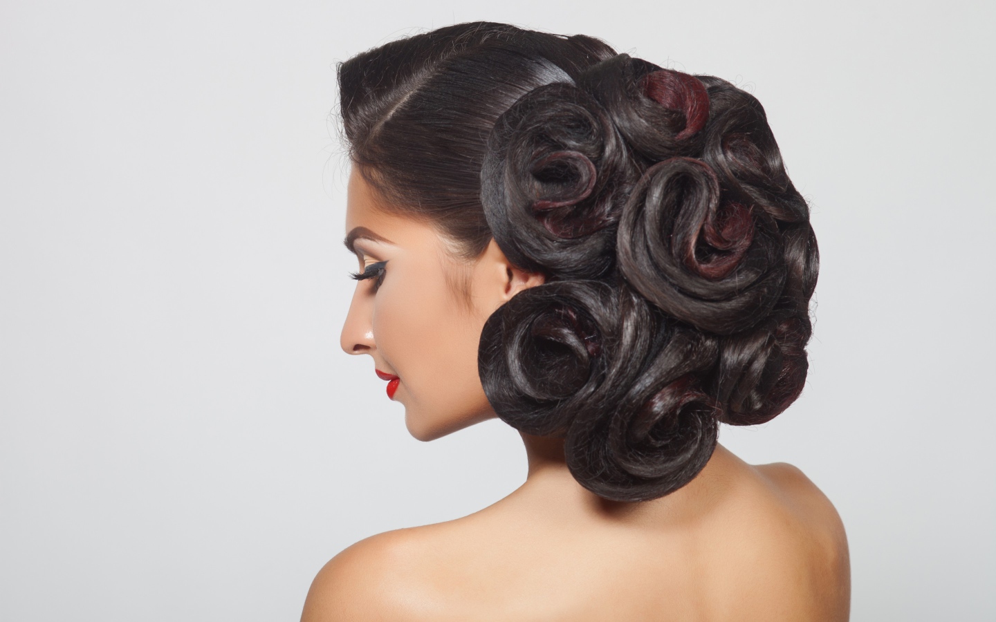 Молодая девушка с красивой прической на сером фоне