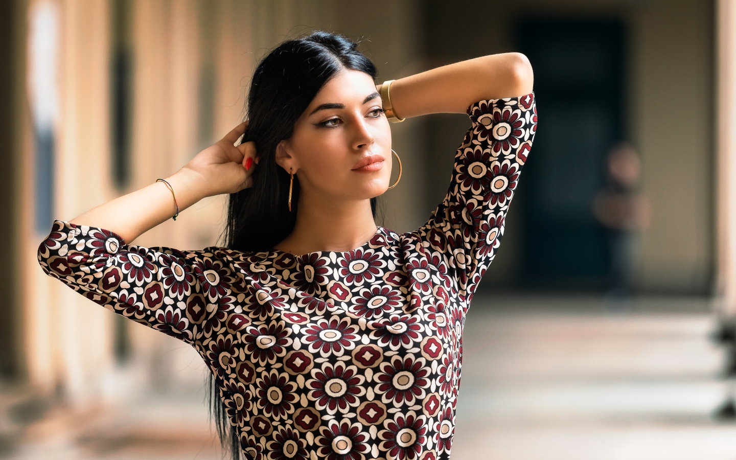 Молодая длинноволосая шатенка с руками в волосах