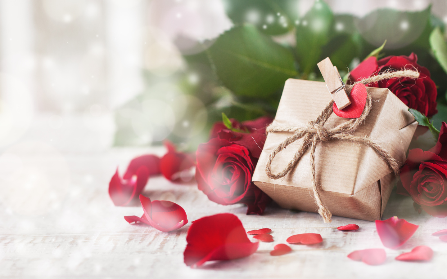 A gift in a box on a table with red roses