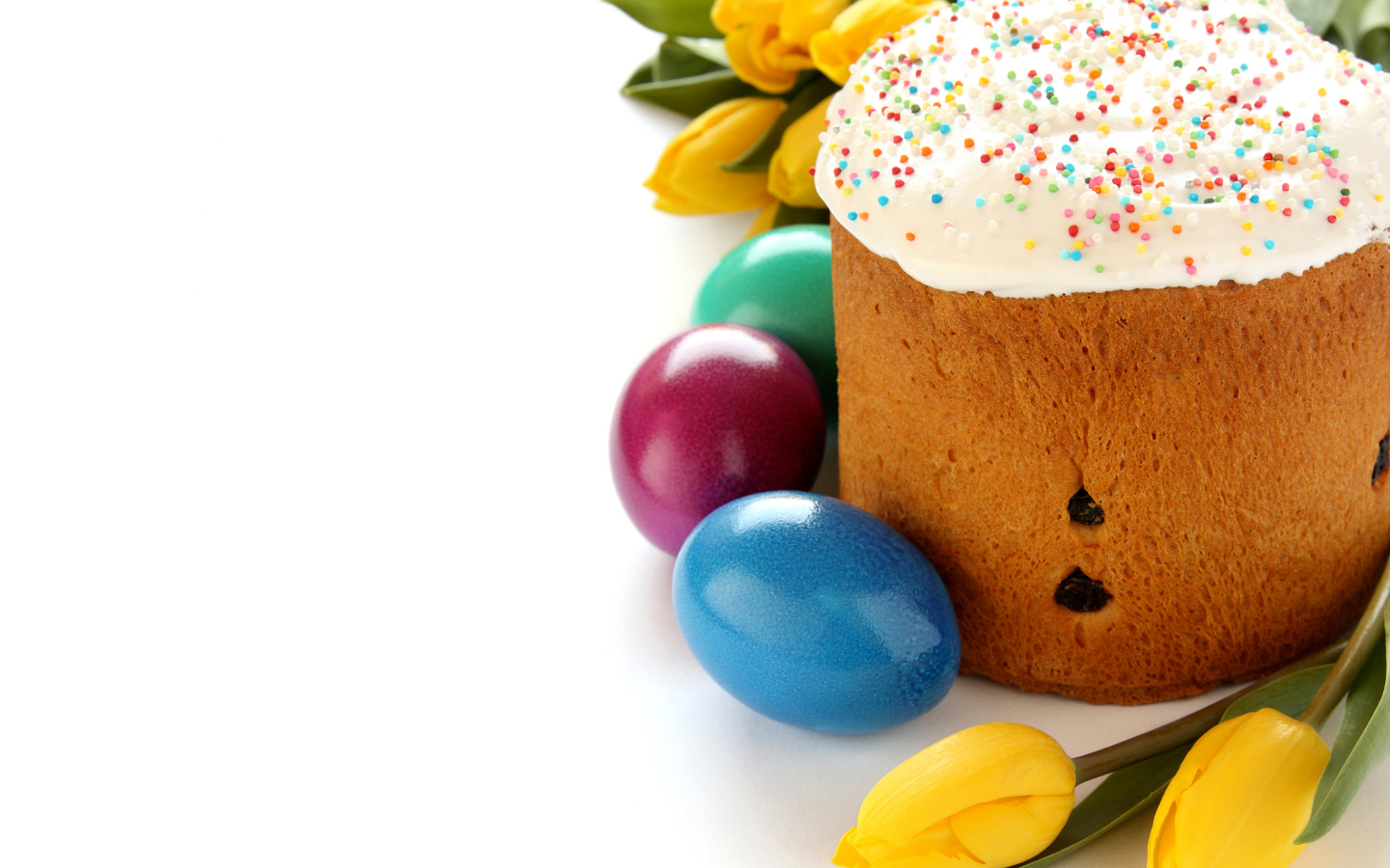 Красивый праздничный кулич с желтыми тюльпанами и крашеными яйцами на белом фоне к Пасхе