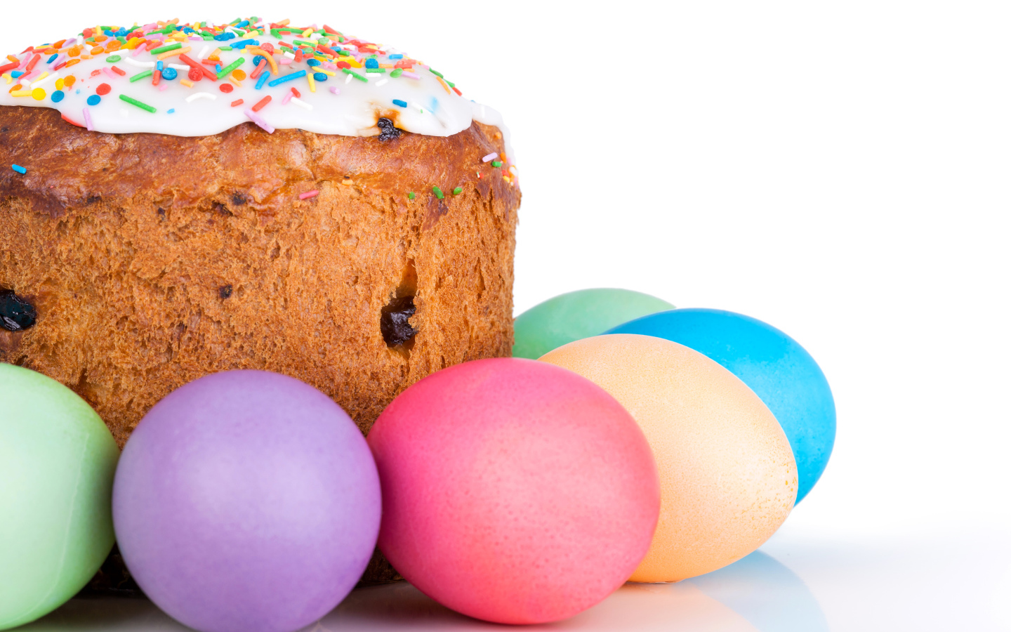 Пасхальный кулич с изюмом на белом фоне с крашеными яйцами 