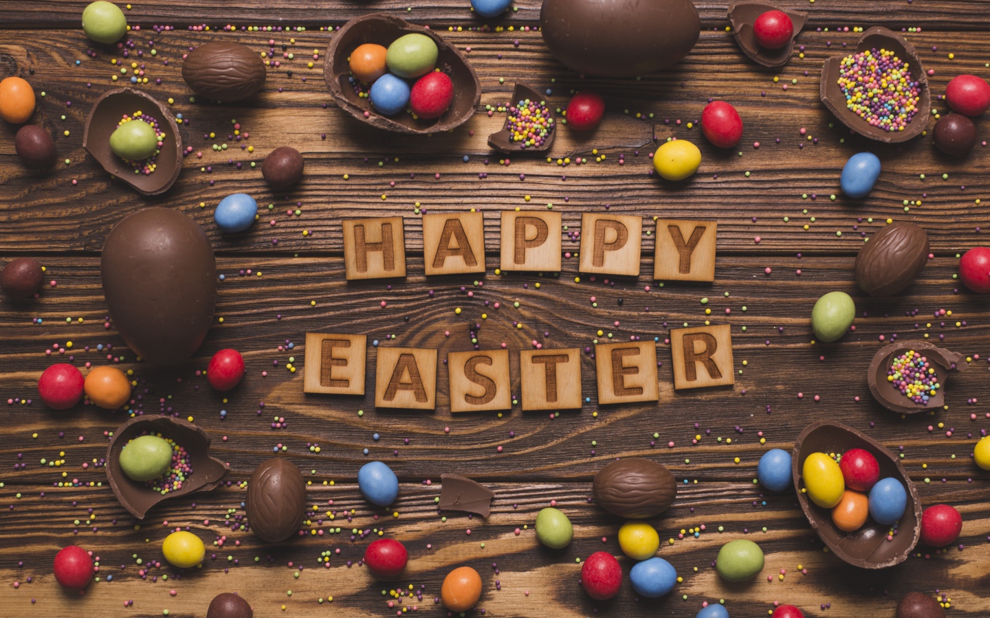 The inscription in English Happy Easter on the table with chocolate eggs and sweets